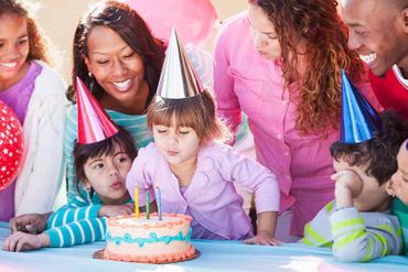 Enfant qui souffle des bougies entouré de sa famille