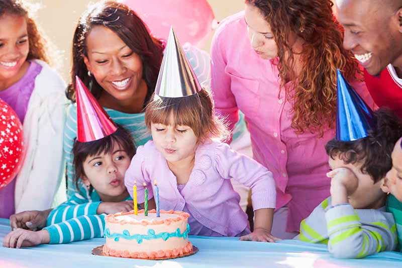 Enfant qui souffle des bougies entouré de sa famille